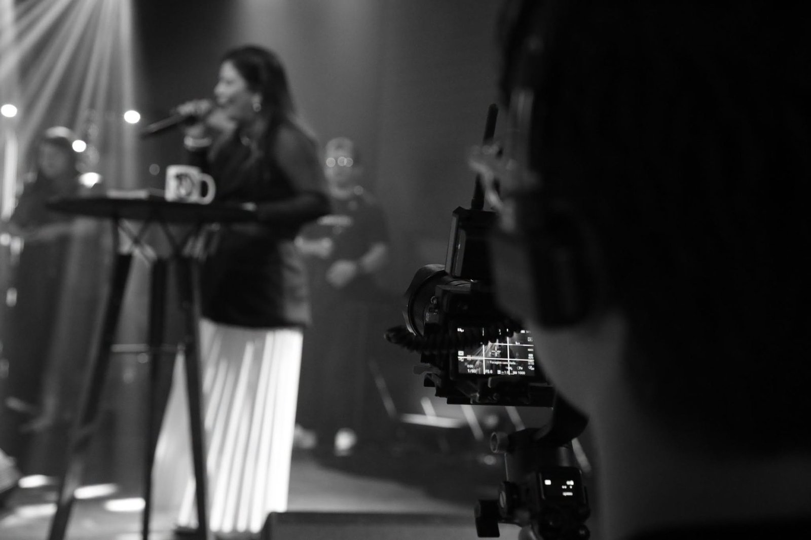 Cantora no palco vista através do monitor de uma câmera de vídeo, durante um culto
